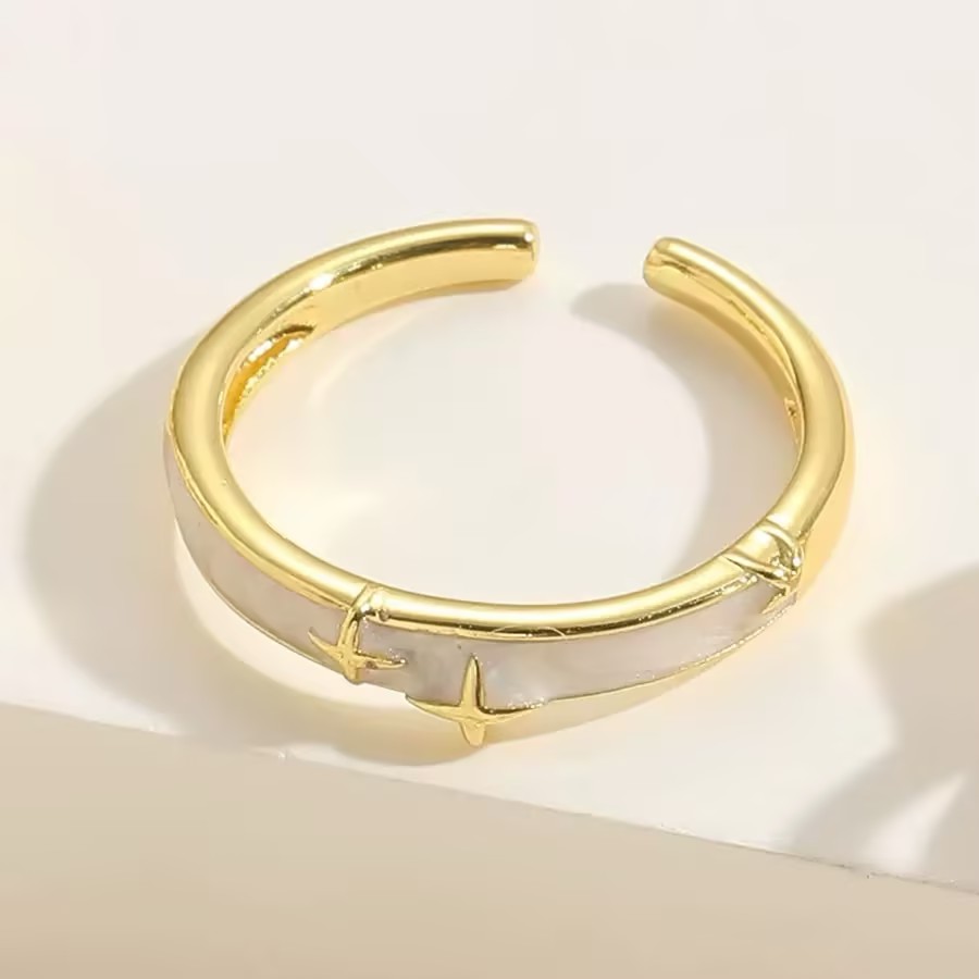 A gold-tone open ring with a pale inset and small star-shaped decorations.